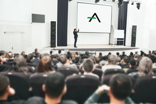 voller Vorlesungssaal mit norelem Academy Logo auf der Leinwand