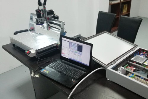 Tisch mit Computer, CNC Router und zwei schwarzen Stühlen