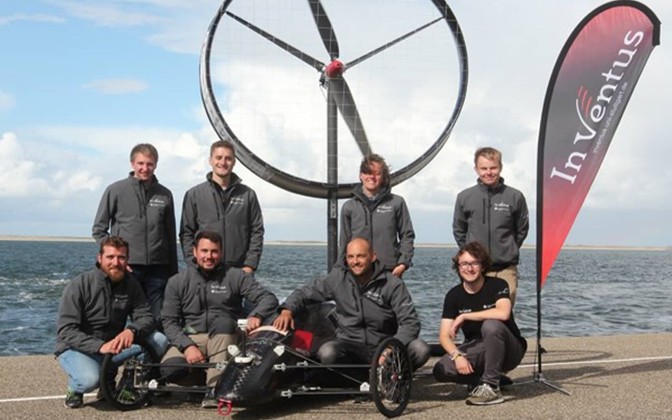 8 Teammitglieder vom Team InVentus in schwarzen Jacken mit ihrem Windkraftwagen in der Mitte